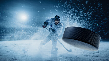 Ice Hockey Rink Arena: Professional Player Shooting the Puck with Hockey Stick. Focus on 3D Flying Puck with Blur Motion Effect. Dramatic Wide Shot, Cinematic Lighting.