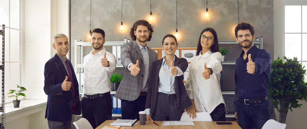 Business team is showing thumbs up by recommending the best corporate service or good career growth. Portrait of a group of different successful businessmen in the office. Concept of successful work. - obrazy, fototapety, plakaty 