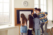 Modern school learning method for children education. Young caucasian female teacher teaching schoolchildren group reading clock time, minutes and hours. Tutor with students standing at class board