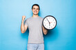 © F8  \ Suport Ukraine - Young caucasian man holding alarm clock cheering carefree and excited on blue background. Victory concept.