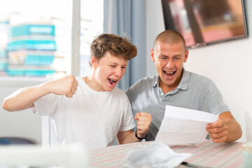 Son and dad feeling happy because they're reading letter that contains glad tidings.