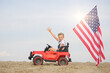 © Jacek - A boy with an American flag in a small toy car.