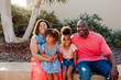 © Erin Brant/Stocksy - Smiling Black family sitting outdoors