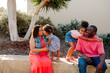 © Erin Brant/Stocksy - Girls hugging seated parents outdoors