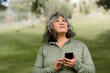 © McKinsey Jordan/Stocksy - Woman Looks to the Sky While Holding Her Phone