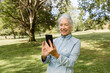 © McKinsey Jordan/Stocksy - Senior Woman Checks Her Phone in the Park