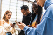 © Kike Arnaiz/Stocksy - Multiracial friends browsing smartphones on street