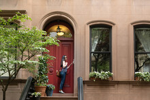 Woman Ringing Doorbell On Brownstone