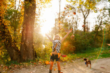 Young Girl Throwing Leaves Up In The Air. 