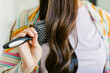 © ByLorena/Stocksy - Unrecognizable woman brushing long dark hair