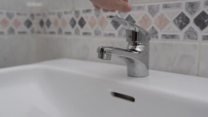 Wall Mural - A hand turning on the faucet and leaving the water running - shot in HD