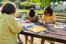 Children Doing Homework At Picnic Table Outdoor