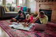 © Erin Brant/Stocksy - Father and boys in living room with map