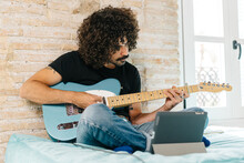 Man With Tablet Learning To Play Guitar