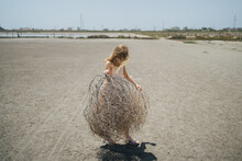 Girl With Dry Plant Playing On The Sand
