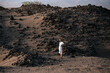 © David Prado/Stocksy - African woman standing on volcanic sand dune on beach