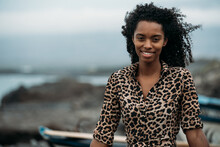 Black Woman Sitting On Boat Near Seashore With The Ocean Background
