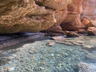 Canvas Print - Pebbles beach in beautiful rocks at summer. Turquoise transparent sea water. Paradise lagoon secluded place for relax. Scenic coastal island landscape. Stones and smooth gravel on ocean floor.