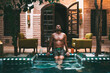 © David Prado/Stocksy - Man sitting on a mosaic floor at the swimming pool