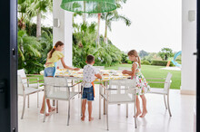 Children Setting A Patio Table For Lunch