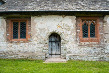 A Wooden Door And Two Windows In A Historic Medieval Church. 