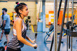 young hispanic latina woman in a gym doing triceps on the pulley
