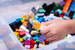 © Kanthita - A child's hand is picking up a plastic block connector in a plastic box to play.