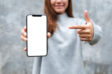 Canvas Print - Mockup image of a beautiful woman showing and pointing finger at a mobile phone with blank white screen