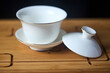 © R_Yosha - Gaiwan on chaban selective focus. Tea ceremony gong fu cha. Chinese white pottery Dehua white Chinese porcelain gaiwan bowl tea cup and lid with gold border on bamboo teaboard tea tray or chaban.