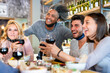 © MandriaPix - dinner at the restaurant of multi ethnic friends, young women and men toasting with red wine, people having fun, facial masks as a protection device below their chin