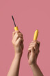 © New Africa - Woman holding mascara for eyelashes on dusty rose background, closeup