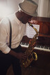© New Africa - African-American man playing saxophone indoors. Talented musician