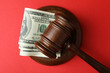 Judge gavel with dollars on red background