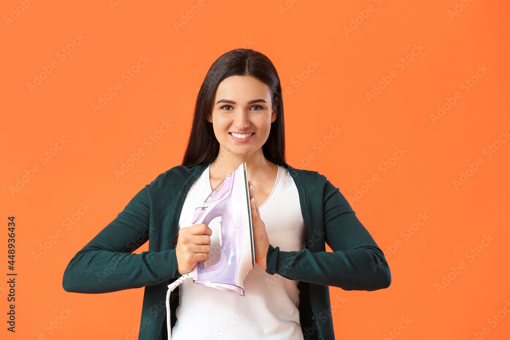 Beautiful young woman with iron on color background