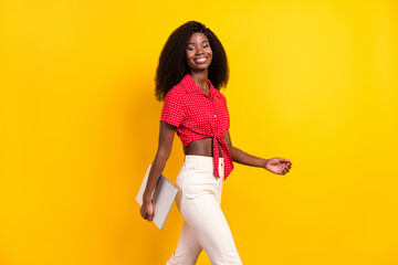 Poster - Profile side photo of dark skin pretty lady go empty space hold laptop smile isolated on yellow color background