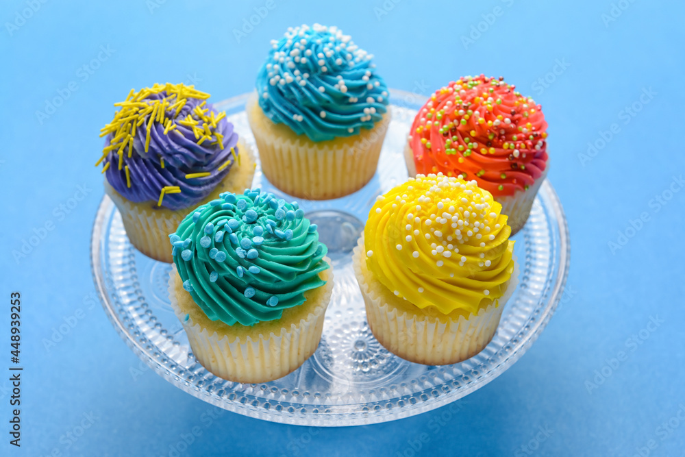 Stand with tasty Birthday cupcakes on color background