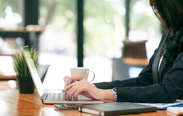 Cropped shot of businesswoman hands working on laptop computer while sitting at her office desk.