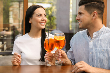 Canvas Print - Happy couple clinking glasses of Aperol spritz cocktails outdoors