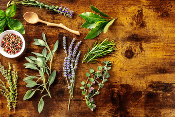 Wall Mural - Fresh aromatic herbs, shot from above on a rustic wooden background with a place for text, a flat lay. Bunches of culinary plants