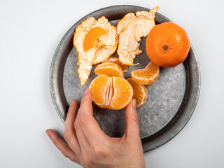 Wall Mural - Woman peeling tangerines on a metal plate