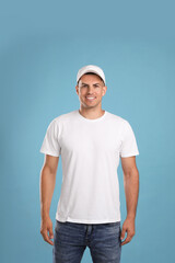 Wall Mural - Happy man in white cap and tshirt on light blue background. Mockup for design