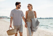 © Syda Productions - leisure, relationships and people concept - happy couple with picnic basket and blanket walking along beach