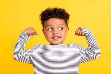 Photo portrait cheerful small boy looking blank space showing strong hands isolated bright yellow color background