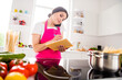 © deagreez - Photo portrait woman in pink apron writing recipe in blocknote cooking pasta talking on cellphone