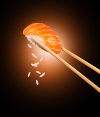 Wall Mural - Fresh traditional japanese sushi with salmon between chopsticks on black background