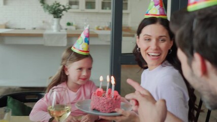 Wall Mural - Little girl blowing candles on birthday cake while celebrating with family 