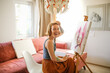 Creative red-haired girl hipster woman with paintings in home workshop, girl draws, creativity and self-expression, creative professions and unusual people