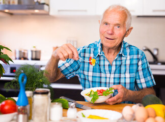 elderly man eating fresh vegetable salad at home