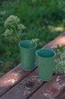 Two green ceramic glasses stand on a wooden surface