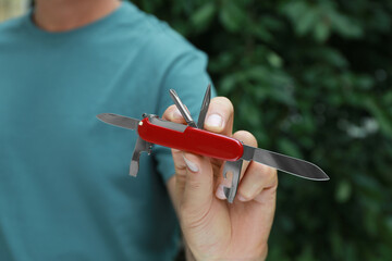 Man holding compact portable multitool outdoors, closeup